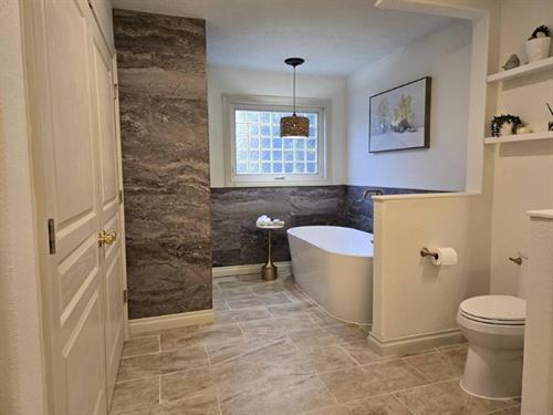 The stunning result of our custom bathroom remodel in Brighton. The new, open-concept layout features a spacious walk-in shower, a freestanding soaking tub, and a beautiful granite-topped vanity. The heated ceramic tile floor adds a final touch of luxury.