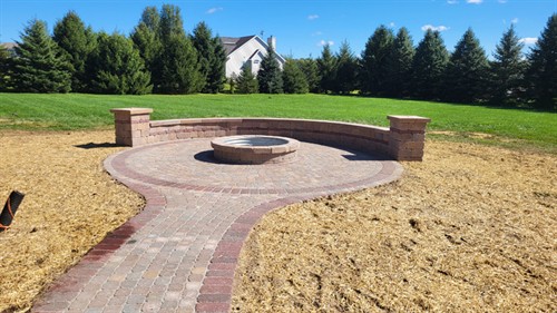 Custom brick firepit with metal ring, including brick retaining wall and patio with walkway access