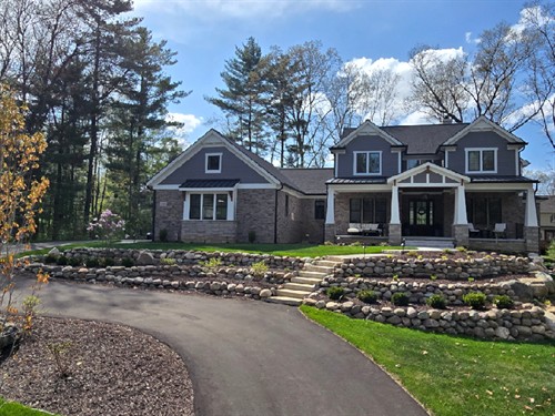 Residential landscape with natural boulder retaining wall and ledge rock steps and paver walkway