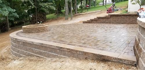Backyard retaining wall with a fire pit and paver patio.