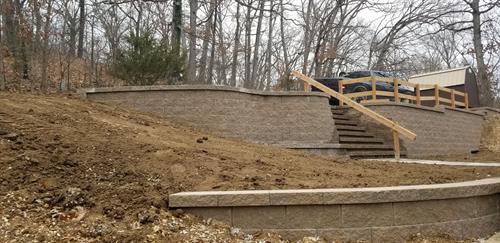 Retaining wall to hod up the road in front of a house with steps down to the house.