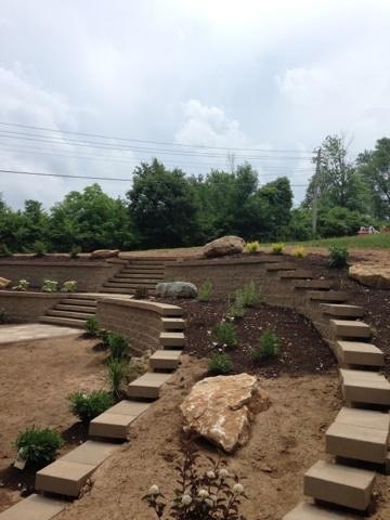 A two tier retaining wall with boulders and landscaping.