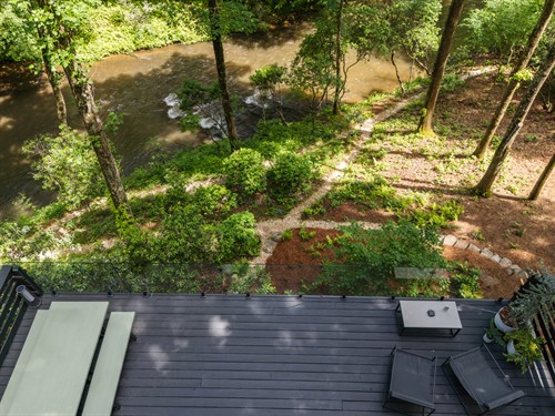 Example of our glass railing and panoramic Toccoa River view, accented with minimalist concrete furniture that complements the retreat’s modern wabi-sabi design and connection to nature.