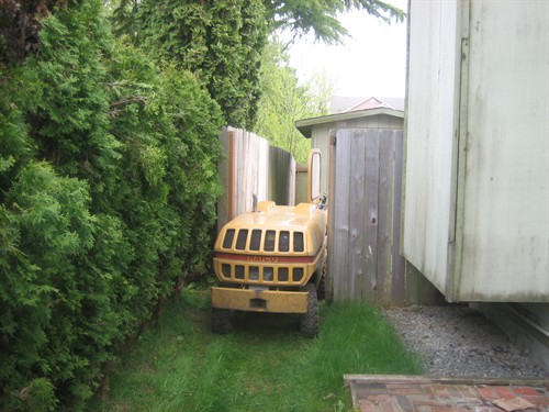 Professional stump grinder passing through a narrow 36-inch gate to reach a backyard stump removal project. Owner-operator Robert Loeder of Sno King Stump Grinding specializes in tight-access residential stump grinding throughout Bothell and nearby communities.