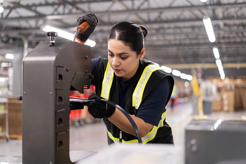 A warehouse worker uses equipment at a workstation.