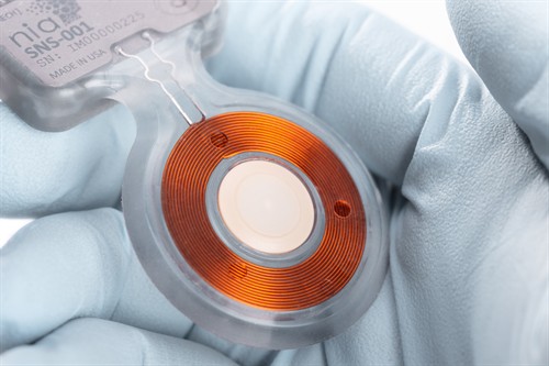 A medical device held in gloved hands.
