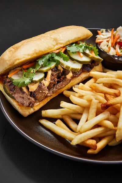 Banh-mi sandwich has mouth watering new york strip and topped with asian pickled cucumber slices, carrots, and fresh cilantro. Served on a Turano roll with chili aioli. 