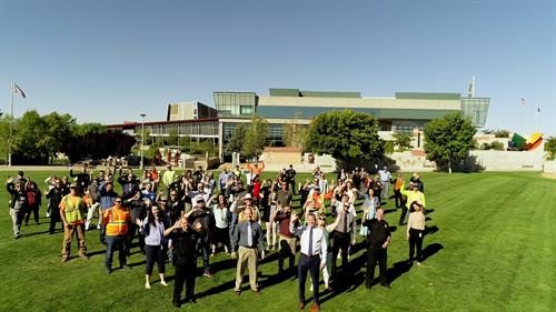 Town staff standing on grass at Civic Center campus waving.