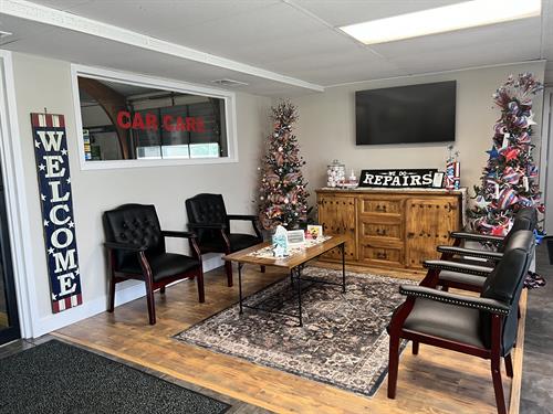 Lobby with seasonal trees, seating, reading material, and television.