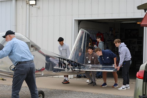 An advisor from EAA chapter 75 and students from the PNB Aviation Club get ready to move the airpline they built. 