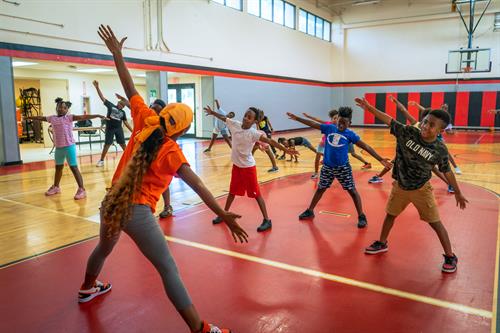 Instructor leading youth through a warm-up before beginning dance fitness session