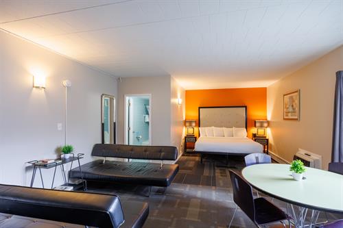 The Social Executive King: Our warm 1st floor room, sociable space with boutiques touches. Perfect for guests needing added workspace and a more unique seating arrangement. This modern decorated room offers a King size bed, two futons, a large table with seating for four, mini fridge, microwave, kitchen cabinets, counter, Tv and Apple Tv.