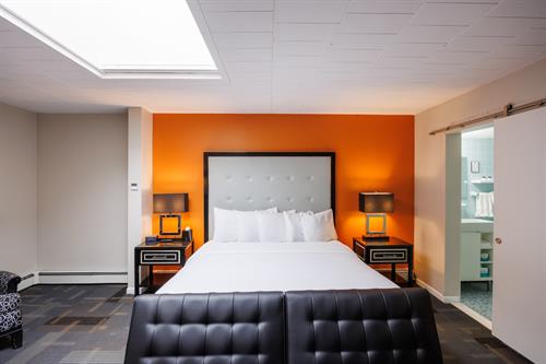 The Retreat Executive King: Our warm 1st floor room, with sociable space and a boutique touches. This modern decorated room offers a King size bed, futon, mini fridge, microwave, desk and chair, bathtub/shower, cabinets and counter with sink, a skylight with motorized shade, 65" Tv and Apple Tv.