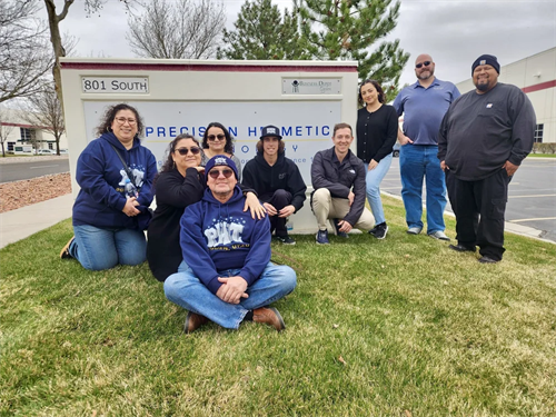 Gallery Image Employees_in_blue_sweashirts_sitting_on_grass_in_front_of_PHT_sign.png