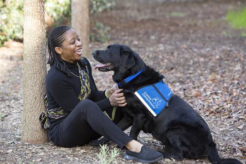 A Canine Companions client sitting on the ground with her Canine Companions service dog, enjoying time together. 
