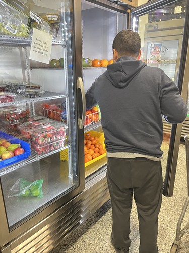 WFCM client selecting fresh fruit.