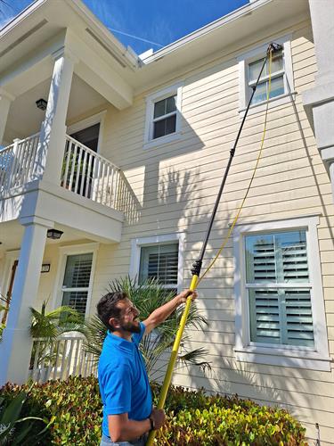 Alex using a water fed pole to clean second story windows in Jupiter.