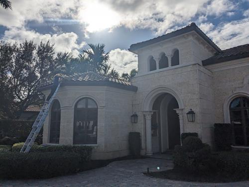 Letizia cleaning gutters on a tall home in Palm Beach County.