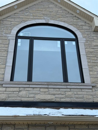 Custom black arched window installation by EcoTech Windows & Doors, combining distinctive architectural style with energy-efficient performance.