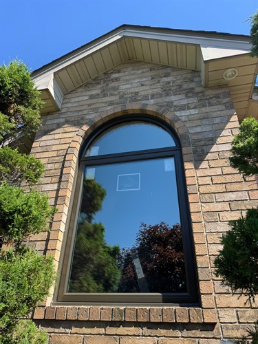 Custom black arched replacement window from EcoTech Windows & Doors, designed to enhance energy efficiency, architectural character and curb appeal.