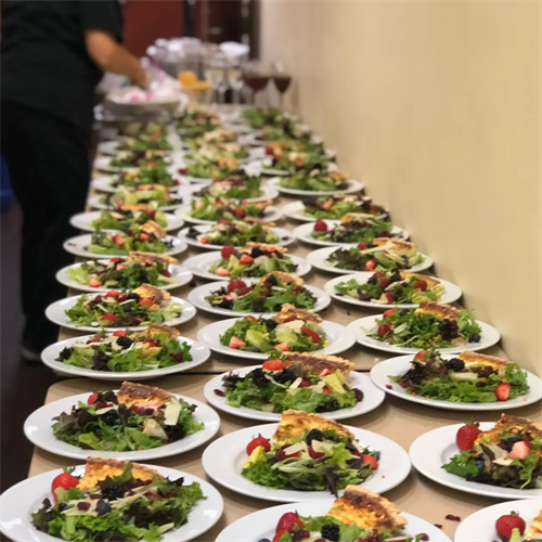 A fresh lineup of chef-crafted salads, prepped and plated to perfection for a large-scale event.