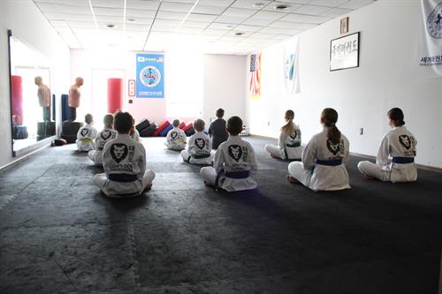 Lion's Den Taekwondo students sit attentively during a class session, demonstrating focus and discipline in their training environment.