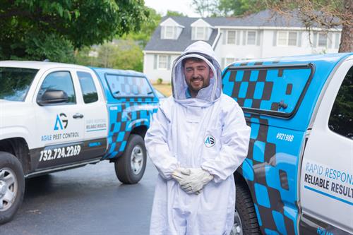 An Agile Pest technician dons a protective bee suit before safely handling a hive