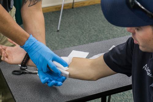 First Aid Instructor, Aaron Kamm teaching a participant how to bandage a wound