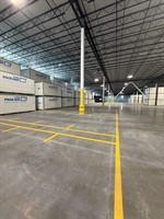 Full warehouse floor striping with yellow lane markings between stacked storage containers