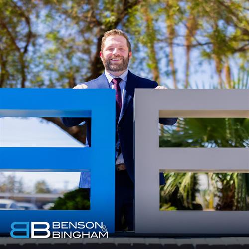 Jordan Kingsley of Benson & Bingham Law Firm poses behind the firm’s logo at the Downtown office, dedicated to helping clients with car accident cases