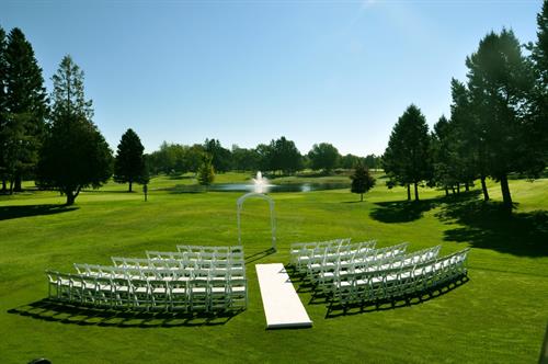 Ceremony Site in Ludington with our White Resin Chairs and Wood Arch