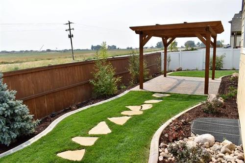 A small backyard including a paver patio, pergola, grass, irrigation, stepping stones, and planting completely installed by Front Range Landscape LLC
