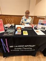Neon Edge education table at a conference, Attorney Jewell sitting at table with Estate Planning materials