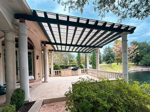 Dark stained cedar pergola top with a poly carbonate roofing system sitting on top of casted concrete pillars.