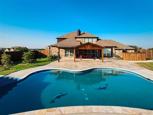 Attached cedar patio cover over looking a massive backyard stamp & stained concrete deck wrapping around a custom freeform 30,000 gallon salt water pool.