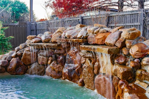 Rock waterfall splashing into a dog pool.
