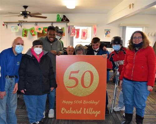 Day program clients with giant card recognizing Orchard Village's 50 years of service