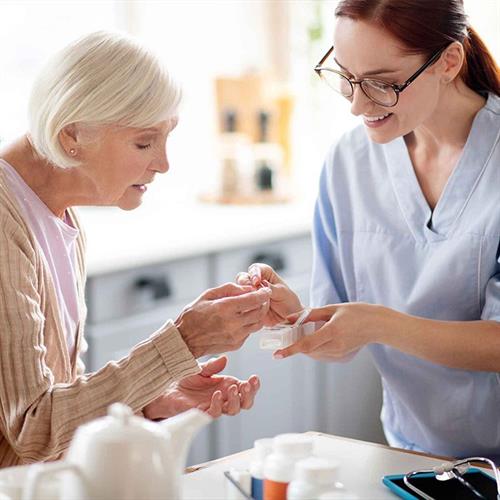 Gallery Image Caregiver-wearing-glasses-giving-vitamins-to-aged-lady-oceanside-ca-1.jpg
