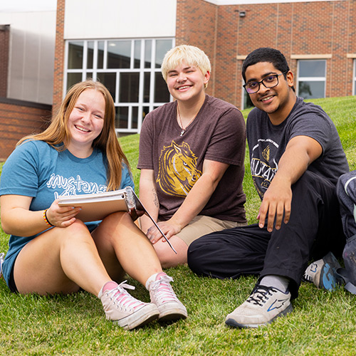 A group of three SMSU students on campus sitting outside