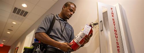 Technician inspects extinguishers in commercial building