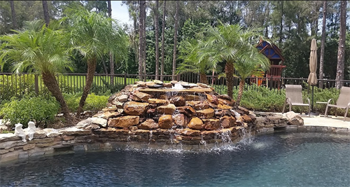 Natural stone cascading water feature on pool