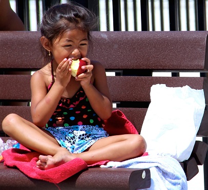 A girl enjoys her apple from our Summer Lunch program