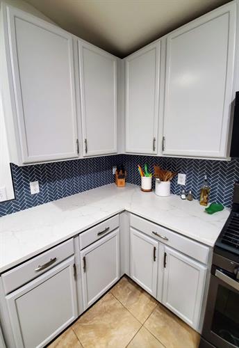 Kitchen Remodel with French Gray Cabinets, Calacatta Valentin Countertops & a Navy BLue Herringbone backsplash in Kyle, TX