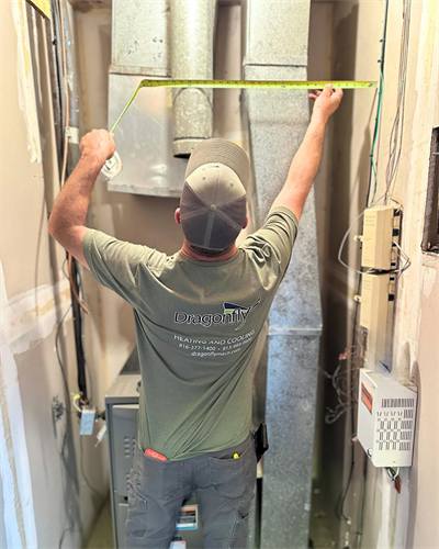 Accurate measurements for a perfect fit. A technician carefully measures ductwork prior to system installation.