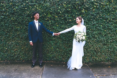 Meija and Darryl posing for a couple’s portrait against a hedge wall in the Garden District.