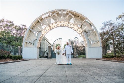Couple portrait beneath the illuminated entrance arch at Armstrong Park.