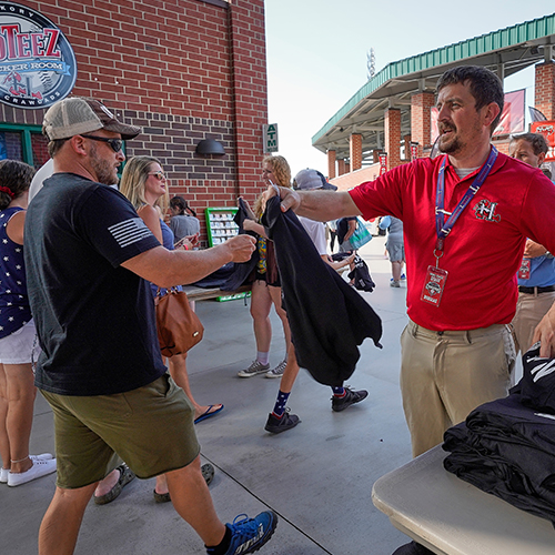 A fan is handed a free tee shirt during a Crawdads giveaway day