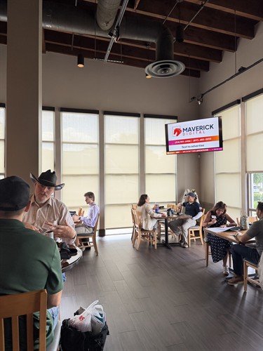 A local café and networking space featuring a Maverick Digital TV screen inviting patrons to text and advertise.
