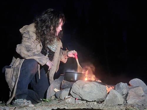 Co-founder, Ansley, cooking a meal over the campfire