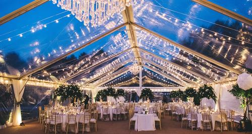 Clear top tent with chandeliers, tables, chairs, flooring